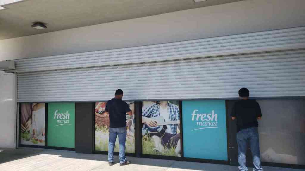 se ver una cortina metalica electrica con dos personas trabajando